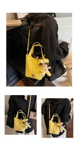 Detail of yellow lychee leather bucket bag with padlock and puppy charm on model