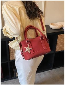 Detail of red Boston bag with gold starfish charm worn as a crossbody bag by a model