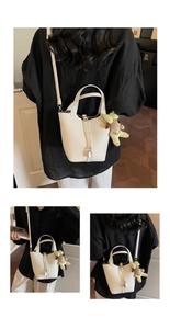 Macro detail of white lychee pattern leather bucket bag with lock and cute puppy charm