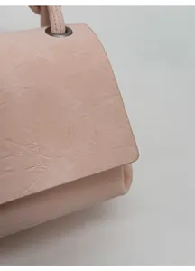 Detail of light pink shoulder bag showing pleated leather texture and metallic hardware