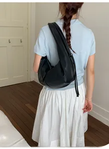 Detail of black pleated hobo bag with side drawstring showing soft matte leather texture