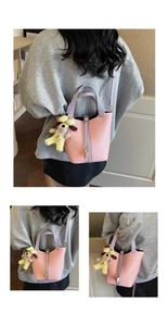 Detail of pink and purple textured leather bucket bag with dog plush keychain charm