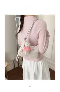 Detail der weißen bedruckten Hobo-Tasche mit Bärenanhänger und Kettenriemen
