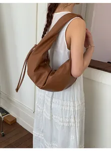 Detail of caramel brown leather hobo bag with side drawstring and natural pleats