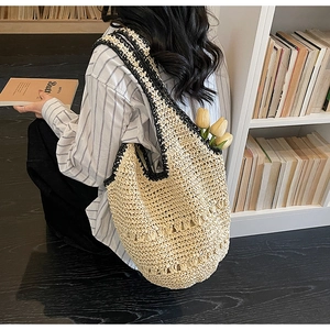 Detail of hand-woven straw tote bag featuring black contrast trim and large capacity design