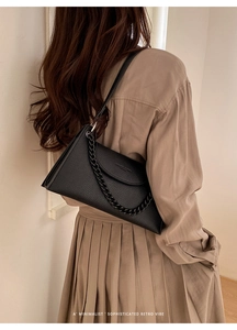 Detailed view of black litchi texture leather shoulder bag with chic chunky chain strap