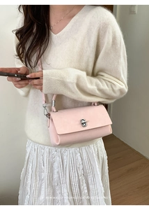 Pink minimalist leather crossbody bag with silver twist lock shown on a model
