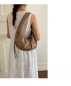 Detailed side view of brown pleated crescent hobo bag with drawstring on model