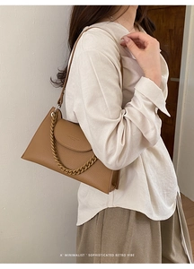 Close-up of brown litchi pattern leather handbag with chain strap and trapezoid shape