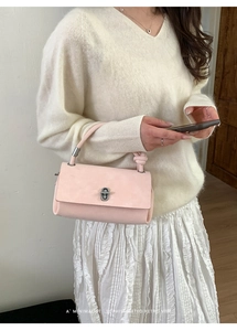 Detail of light pink rectangular crossbody bag with silver twist lock and knotted handle