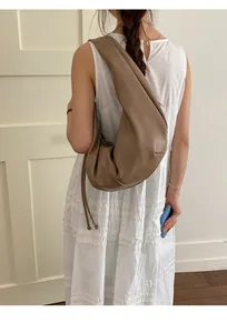 Brown leather crescent tote bag with knot strap detail shown on a model from behind