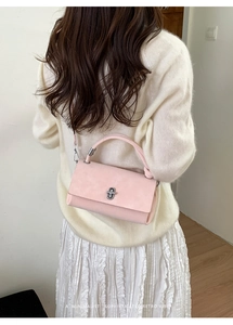 Rear view of a model carrying a vintage pink rectangular crossbody bag with silver hardware