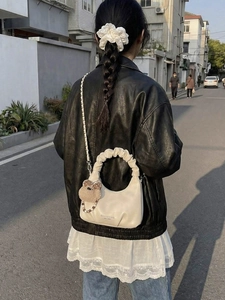 Chic pleated cream crescent bag with teddy charm and beads, styled as a crossbody bag