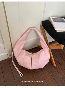 Detailed view of pink pleated leather dumpling bag with side drawstring and zipper closure