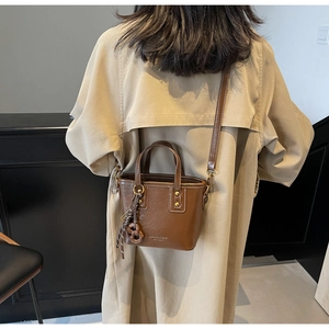Detail of vintage brown bucket bag with gold studs and adjustable strap on a model