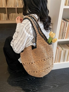 Straw hobo shoulder bag with black trim and hollow weave detail for beach vacations