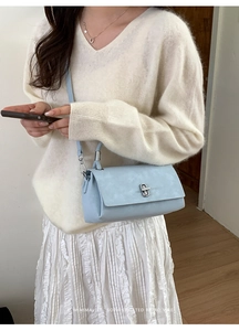 Close-up of a light blue rectangular crossbody bag with a silver metal twist lock