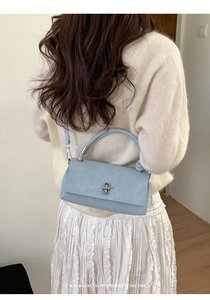 Close-up of a minimalist light grey-blue rectangular handbag with a silver metal turn-lock