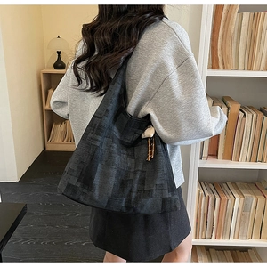 Detail of black geometric jacquard tote bag with stylish long white decorative pendant