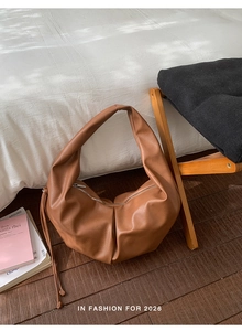 Close-up of brown pleated leather hobo bag showing soft texture and zipper detail