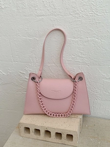 Pink lychee texture trapezoid shoulder bag with decorative chain on stone prop