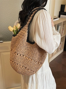 Large beige straw woven tote bag with black handles and hollow stripes for beach vacation
