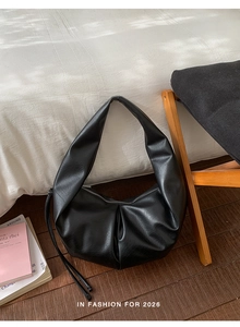Close-up of the pleated black hobo bag texture and zipper on a natural wood surface