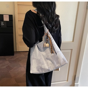 Detail of checkered tote bag with coffee cup charm and woven tassel on the shoulder strap