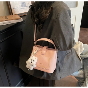 Détail du sac seau rose clair en cuir grainé avec un petit pendentif chien peluche