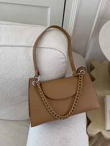 Vintage caramel lychee pattern shoulder bag with decorative chain on a white sofa