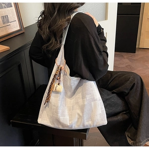 Detail of grey canvas tote bag with contrast patterns and coffee cup keychain on model