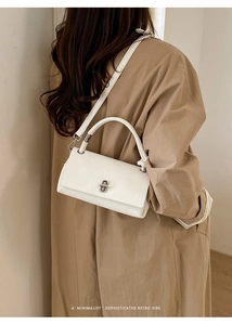 White textured leather handbag styled with a khaki trench coat for a minimalist retro look