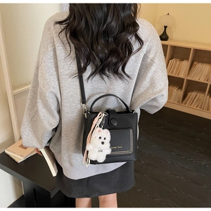 Détail du sac seau en cuir grainé noir avec charme d'ours sur le dos du mannequin