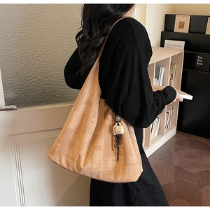 Detail view of large soft leather tote bag in light brown with decorative coffee cup charm