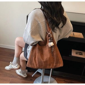 Detailed close-up of brown textured tote bag with a cute white coffee cup pendant accessory