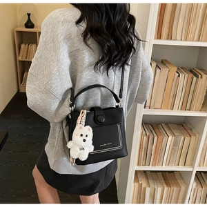 Gros plan du sac seau noir en cuir grainé avec breloque chien et détails de clous dorés