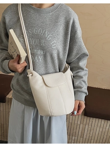 Close-up of off-white bucket bag with lychee texture and vertical stitching detail