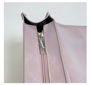 Close-up of silver metal zipper and stitching detail on the light pink leather backpack