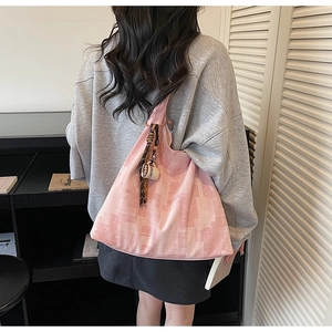Detail of pink knitted tote bag featuring abstract patterns and coffee cup charm