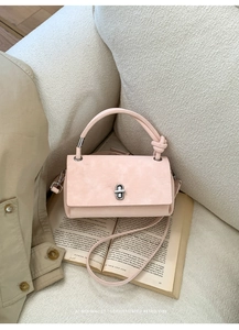 Chic blush pink rectangular crossbody bag on a white textured sofa with a retro vibe