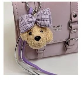 Detail of plush dog keychain with purple plaid bow on a chic small square bag