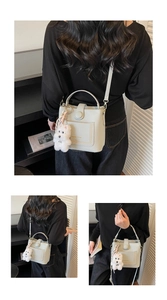 Détail du sac seau beige clair à texture de litchi avec charmant pendentif chiot blanc