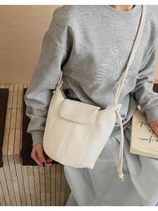 Detail of cream lychee texture leather bucket bag with drawstring and golden hardware