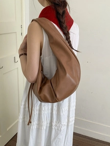 Minimalist brown pleated leather hobo tote bag shown on a model in a casual style