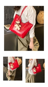 Detail of red wax leather tote bag featuring a teddy bear charm and large capacity