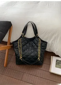 Close-up of black quilted leather tote bag with elegant golden metal chain shoulder strap