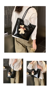 Detail of black glossy tote bag with plush bear charm and spacious shoulder strap design