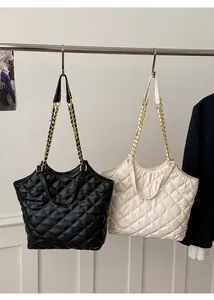 Detail of large tote bags in black and cream featuring quilted pattern and chain straps