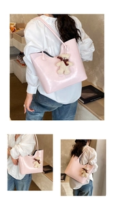 Pink glossy tote bag detail with plush bear charm and spacious shoulder carry design