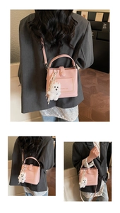 Vue détaillée d'un sac seau rose en cuir grainé avec un petit pendentif de chien en peluche